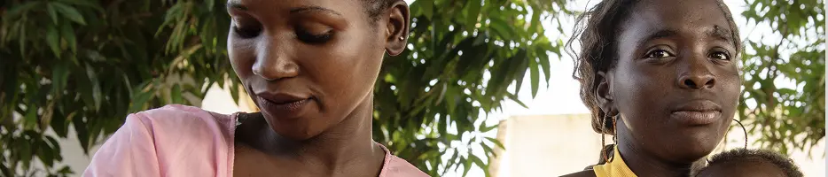 Imagem de duas mulheres amamentando embaixo de uma árvore.